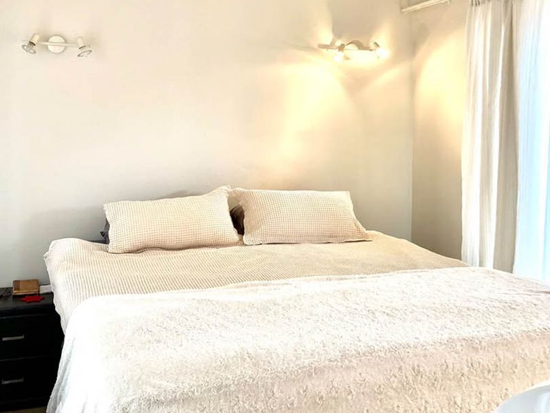 A well-lit bedroom featuring neutral wall tones, wall-mounted accent lighting, and a curtain track for window treatments.