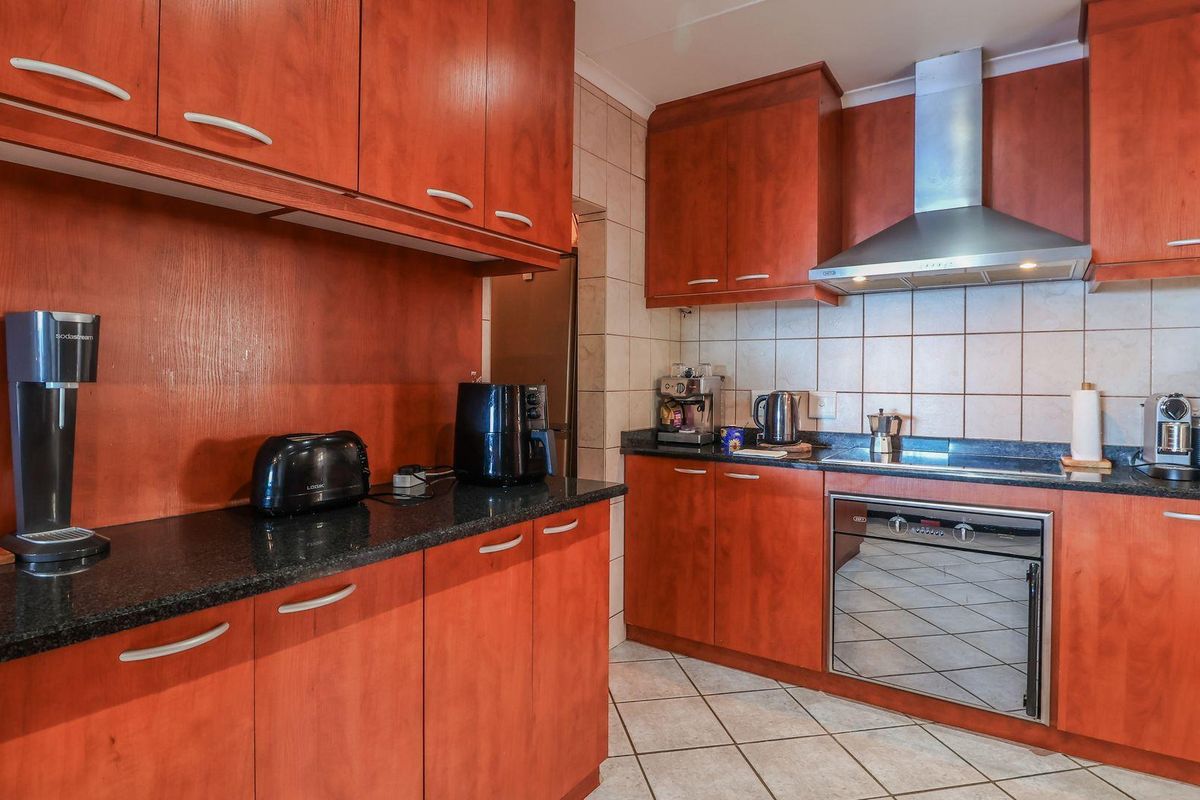 A functional kitchen featuring cherry-wood cabinetry, dark granite countertops, tiled backsplash, and built-in stainless steel oven with an extractor fan.