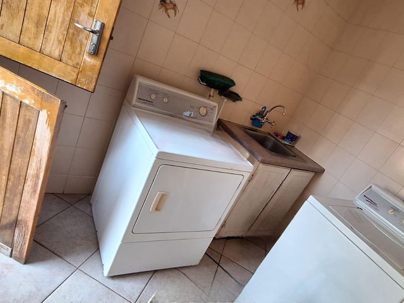 Functional laundry room featuring tiled walls and flooring, a built-in sink with cabinetry, and a traditional stable door.