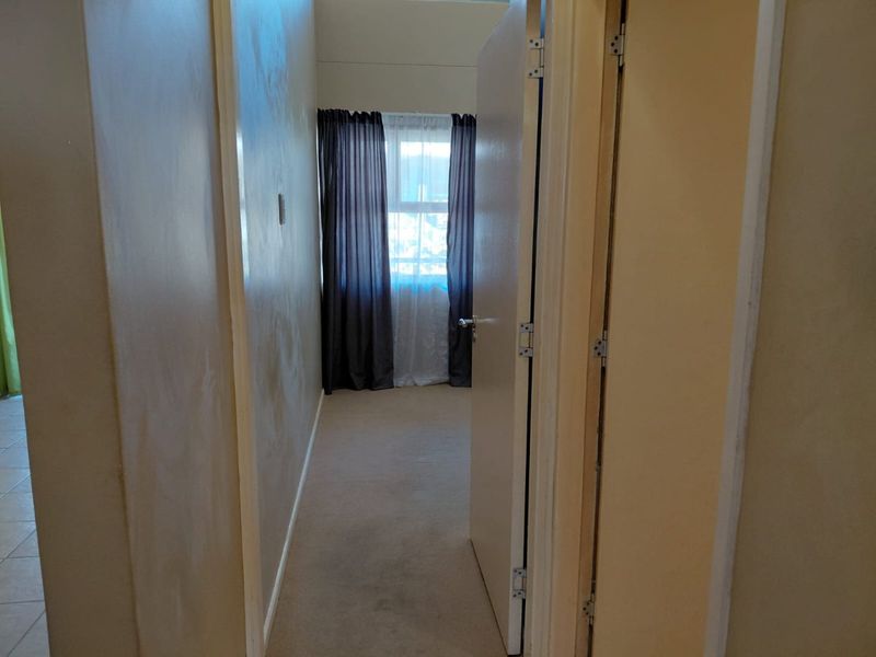 An empty bedroom featuring carpeted flooring and a window, presenting a blank canvas for potential interior updates.