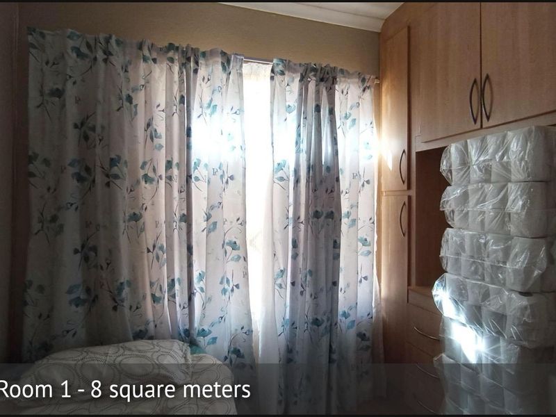 A compact bedroom featuring built-in wooden cupboards and natural light from a window.