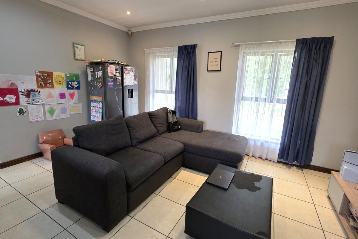 A comfortable living room featuring neutral tiled flooring, recessed downlighting, and large windows that provide natural light to the space.