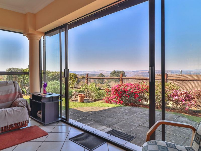 A covered patio area featuring large sliding glass doors that open onto a paved outdoor space with scenic landscape views.