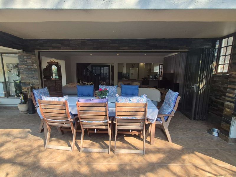 Covered patio featuring stone cladding, built-in braai, and tiled flooring, seamlessly connecting to the indoor living area through large stacking doors.