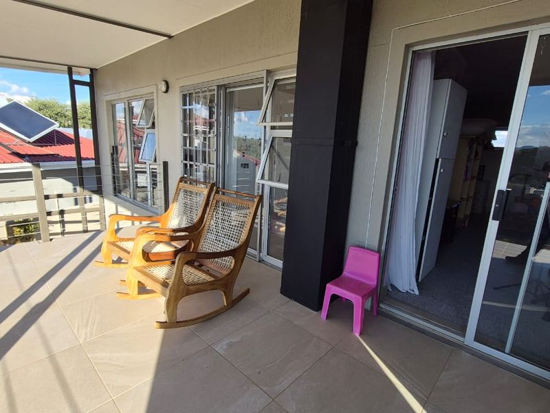 A covered balcony featuring tiled flooring and sliding glass doors, providing a functional outdoor space with views of the surrounding property.
