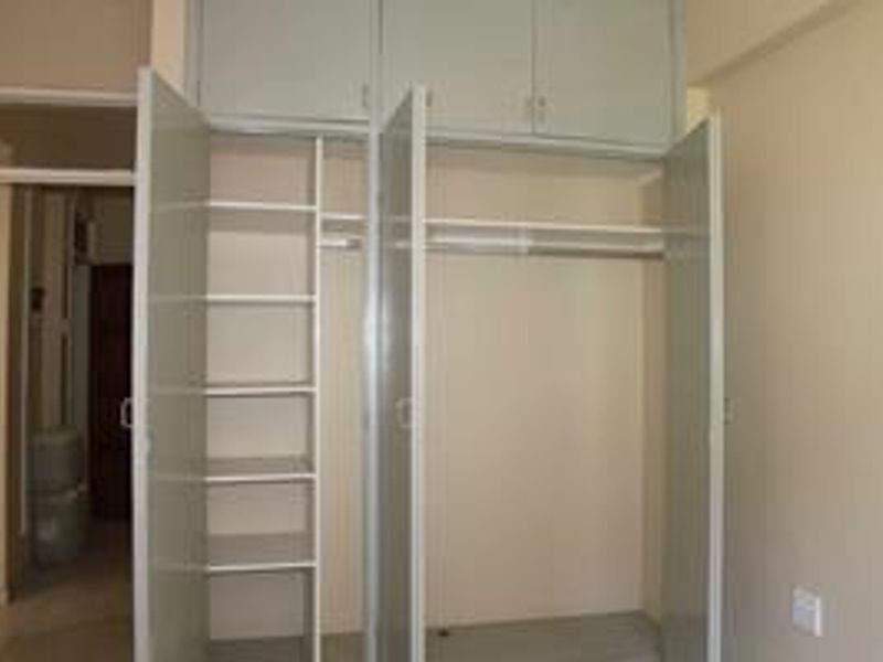 A bedroom featuring built-in cupboards with integrated shelving and overhead storage compartments, providing ample storage space.