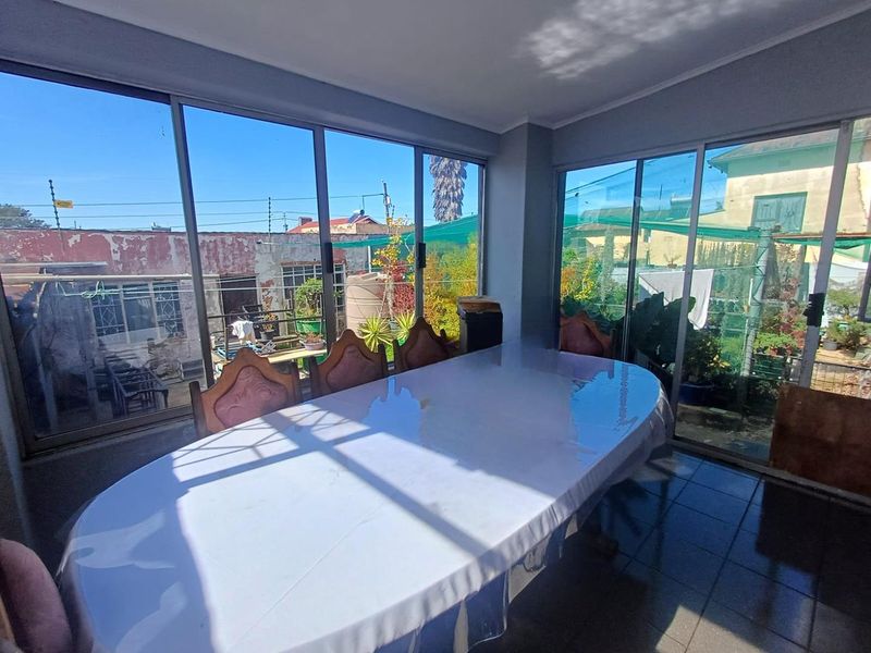 Bright dining area featuring extensive floor-to-ceiling sliding glass doors that provide ample natural light and views of the rear garden.