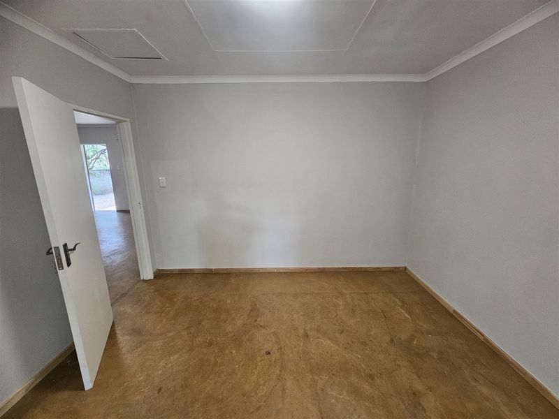 An empty bedroom featuring neutral walls, cove cornicing, and unfinished flooring, offering a blank canvas for renovation or interior design.