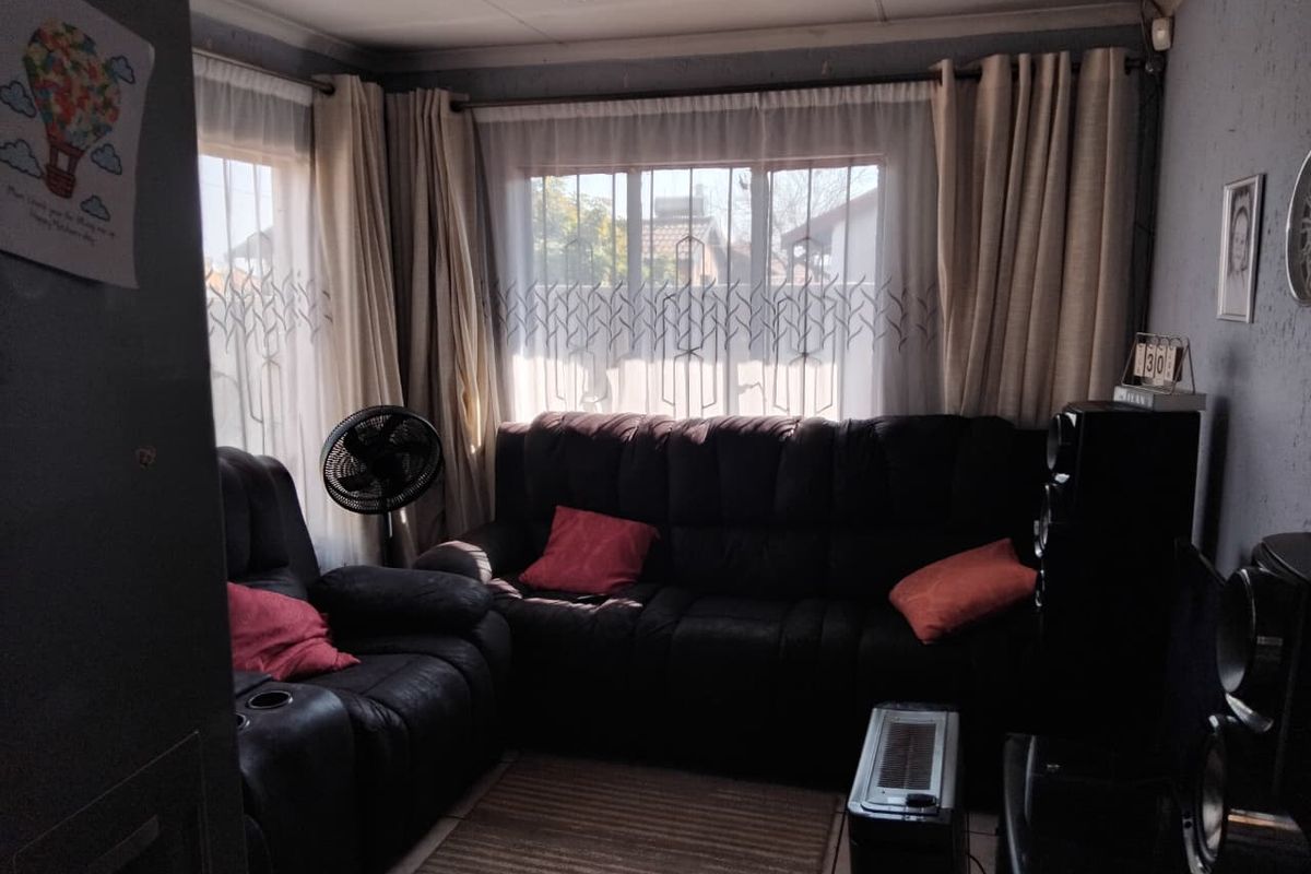 A cozy living room featuring large windows with curtains, providing natural light and a view of the exterior.