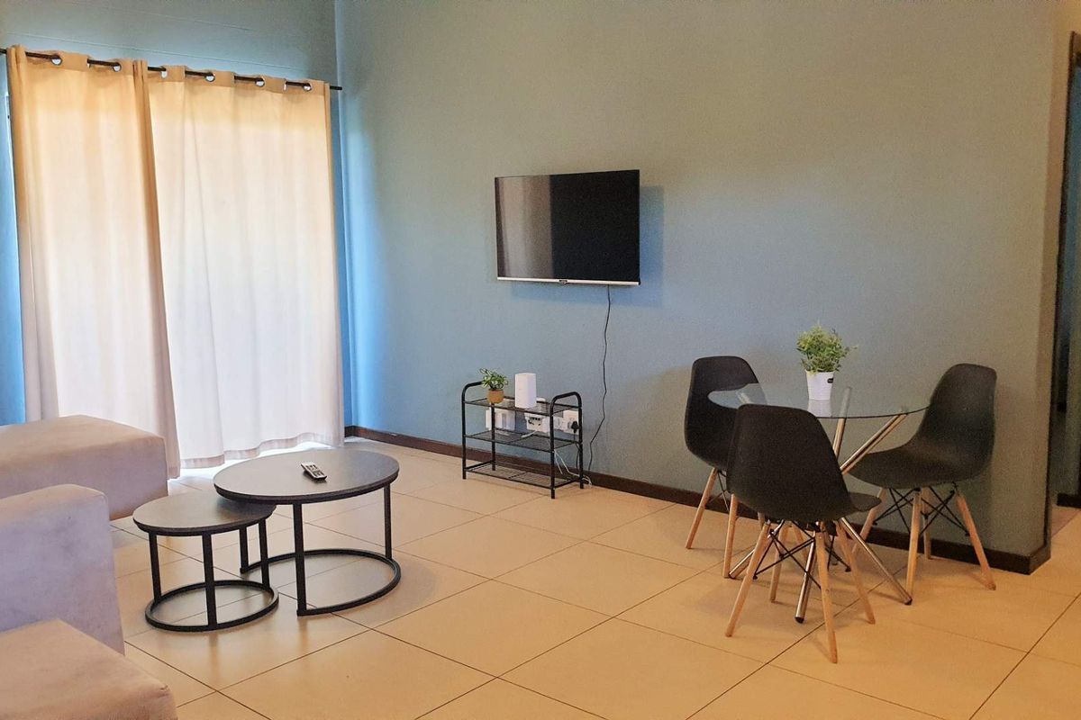 A living room area featuring tiled flooring and a sliding glass door with curtains, providing access to an outdoor space.