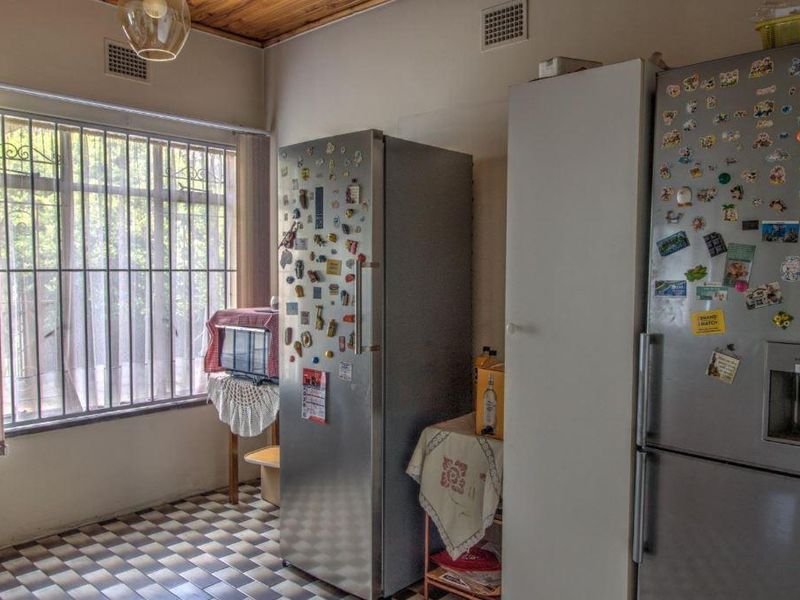 A functional kitchen area featuring tiled flooring, timber ceiling paneling, and security bars on the windows.