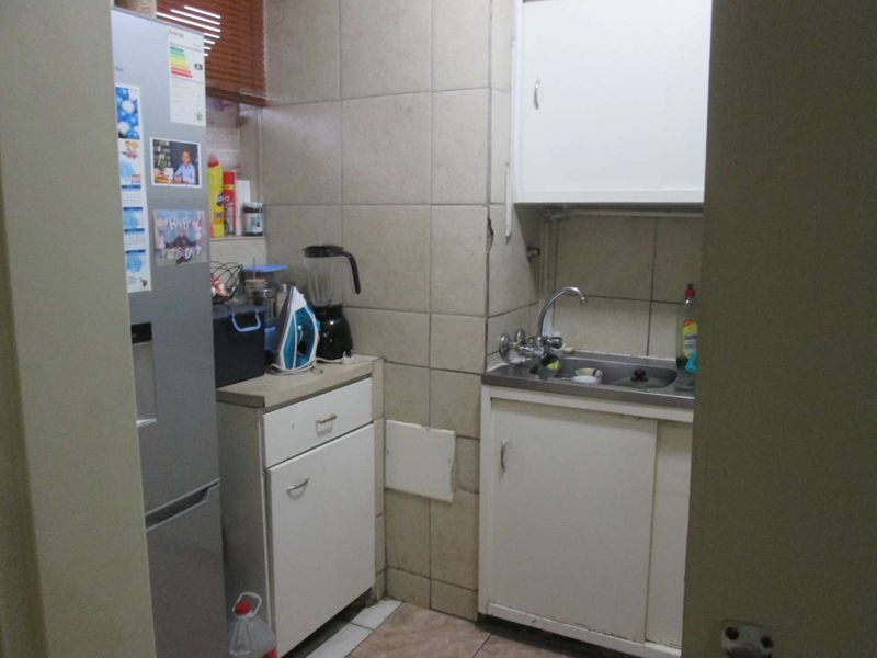 A compact scullery area featuring a stainless steel sink, tiled splashback, and built-in cabinetry, providing functional utility space for the apartment.