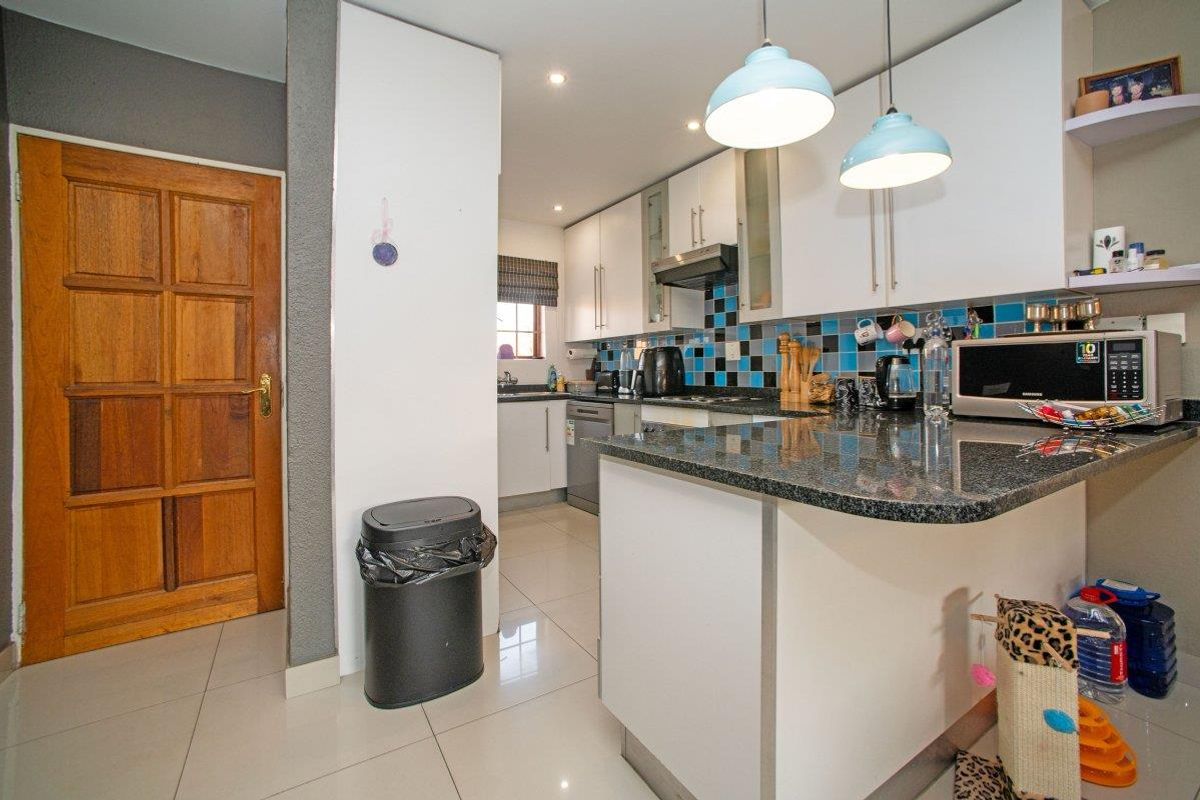 A functional kitchen featuring granite countertops, white cabinetry, a tiled backsplash, and modern lighting, providing a clean and practical workspace.