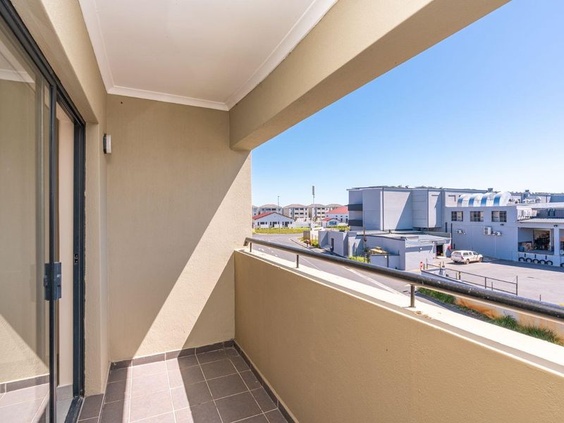 A covered balcony featuring tiled flooring and a metal balustrade, offering an elevated view of the surrounding neighborhood.