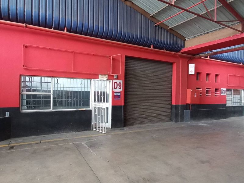Industrial warehouse space featuring multiple roller shutter doors, secure access points, and durable concrete flooring under a high-clearance metal roof structure.