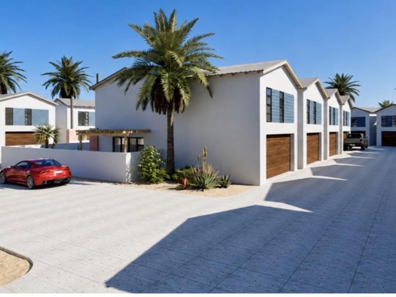 A modern townhouse complex featuring paved driveways, multiple garage access points, and clean architectural lines in a well-maintained estate setting.