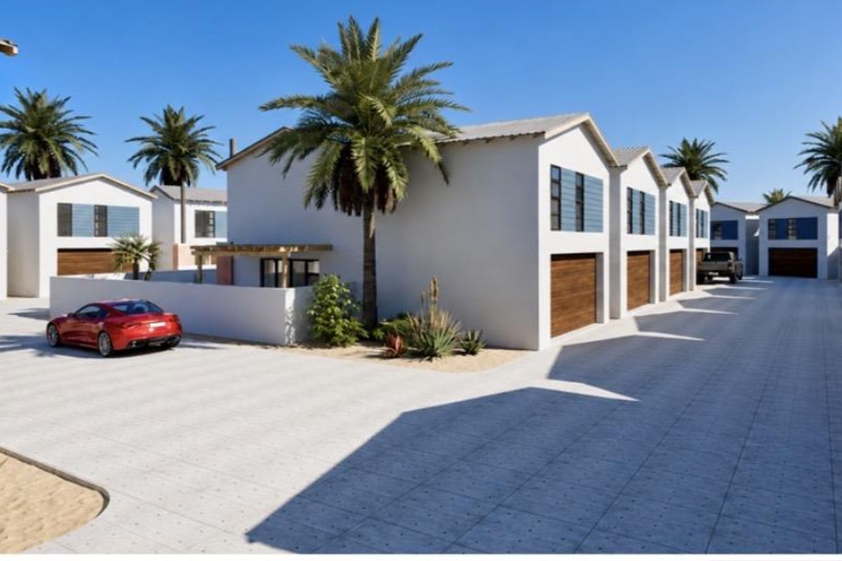 A modern townhouse complex featuring paved driveways, multiple garage access points, and clean architectural lines in a well-maintained estate setting.