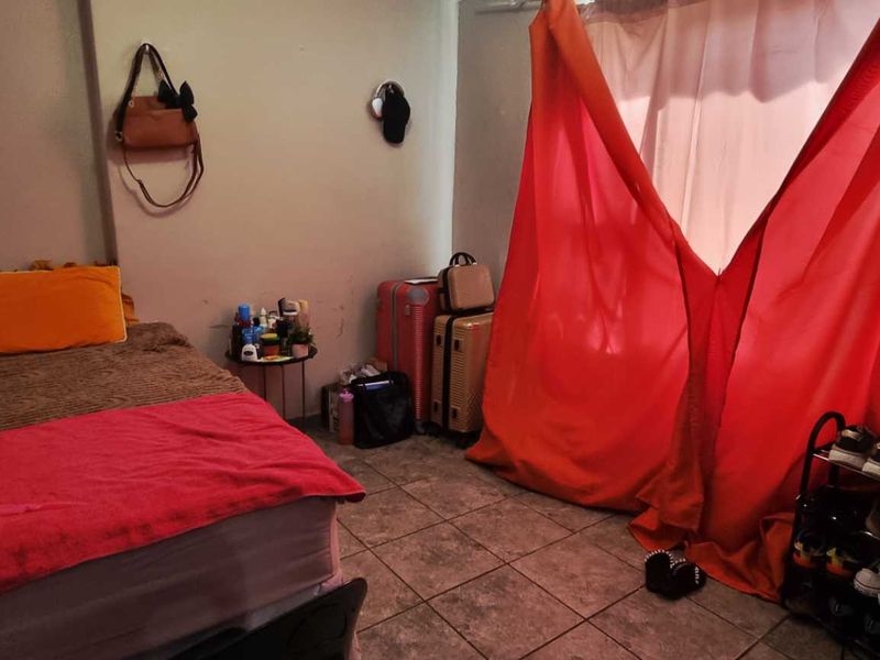 A bedroom featuring tiled flooring and plain walls, currently used as a sleeping area.