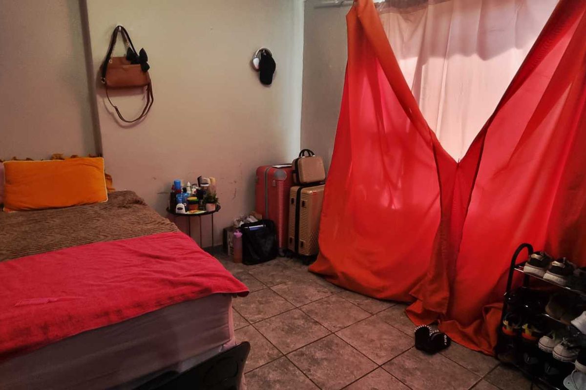 A bedroom featuring tiled flooring and plain walls, currently used as a sleeping area.