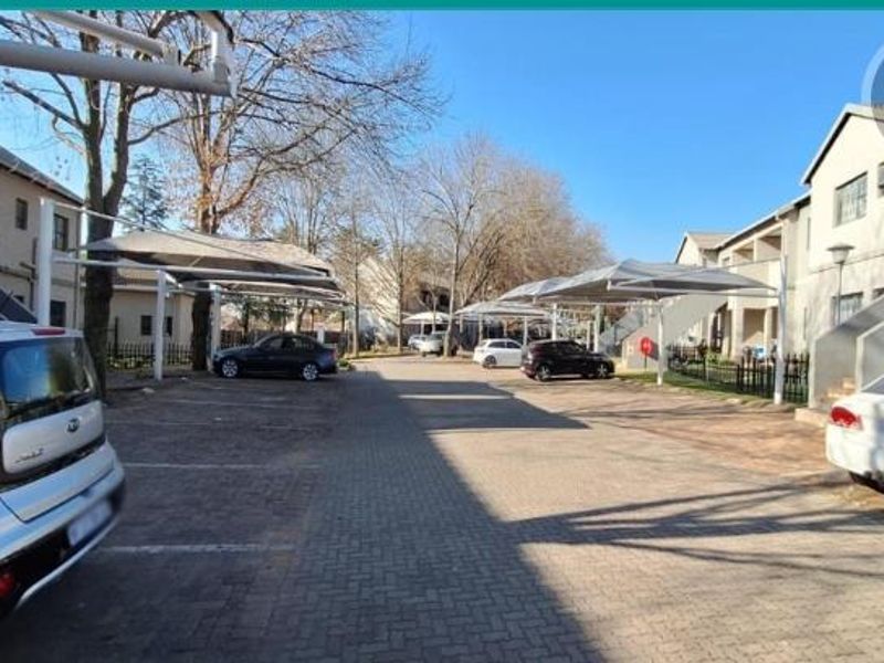 Exterior view of the apartment complex parking area featuring paved driveways and covered shade cloth parking bays.
