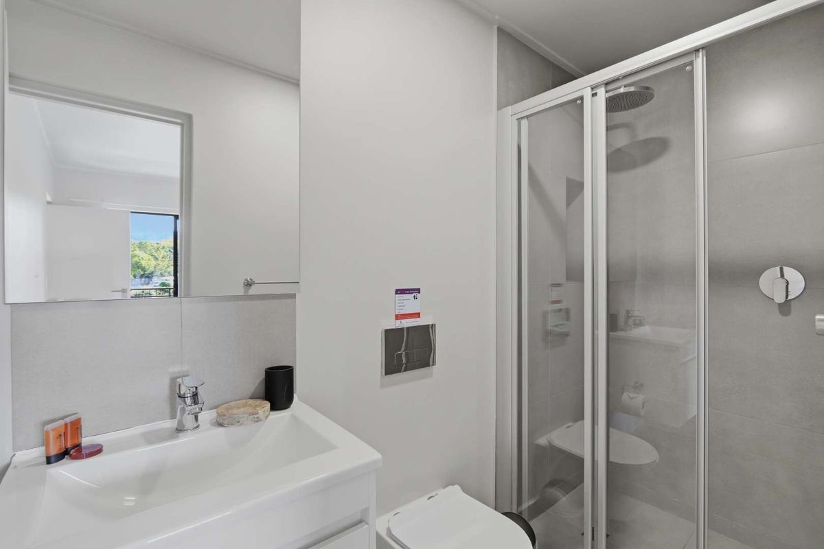 Modern bathroom featuring a glass-enclosed shower, wall-mounted toilet with concealed cistern, and a sleek vanity with a large mirror.