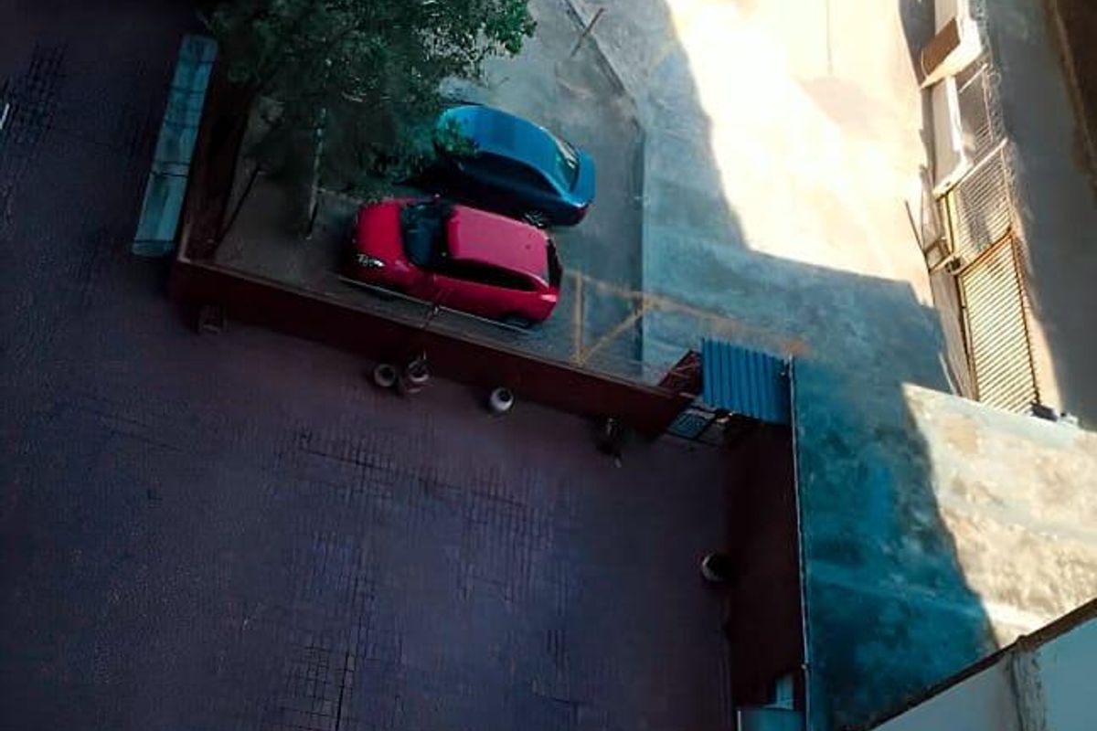 An elevated aerial view looking down onto the apartment complex courtyard, featuring paved surfaces and designated parking areas.