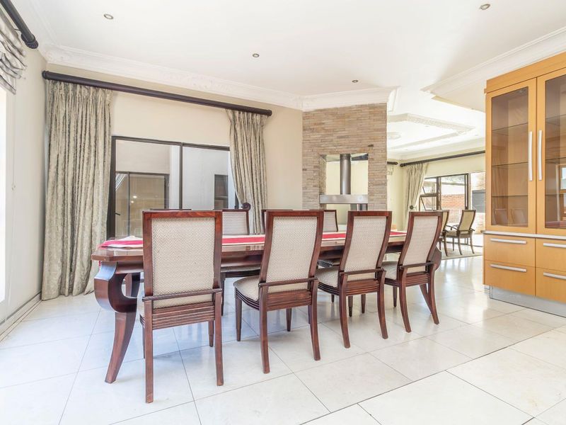 Spacious dining area featuring tiled flooring, a stone-clad fireplace, and a built-in display cabinet, with natural light flowing through large sliding glass doors.