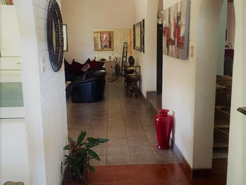 A view through a hallway featuring arched doorways, tiled flooring, and white painted brick walls leading into the living area.