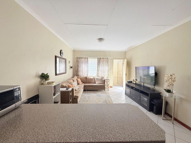 Open plan living area featuring tiled flooring, a kitchen counter, and direct access to the exterior via a security gate.