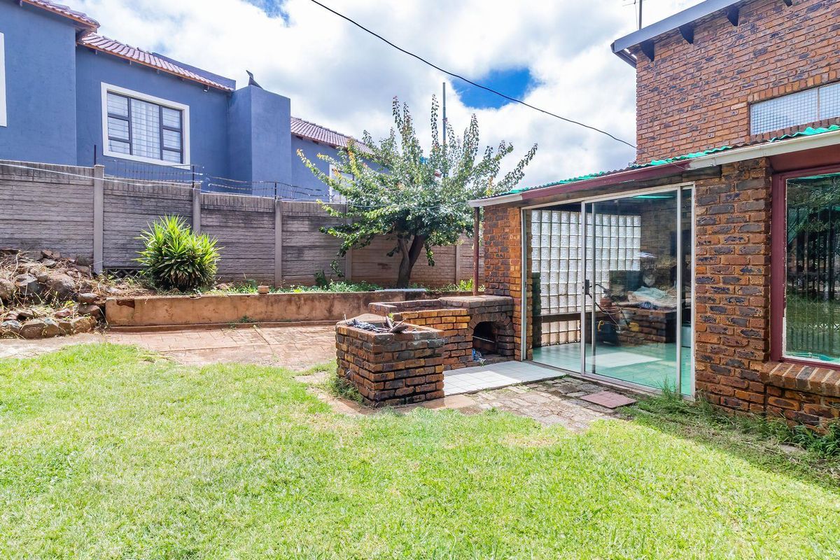 A private rear garden featuring a built-in brick braai area, paved patio space, and established perimeter walling.