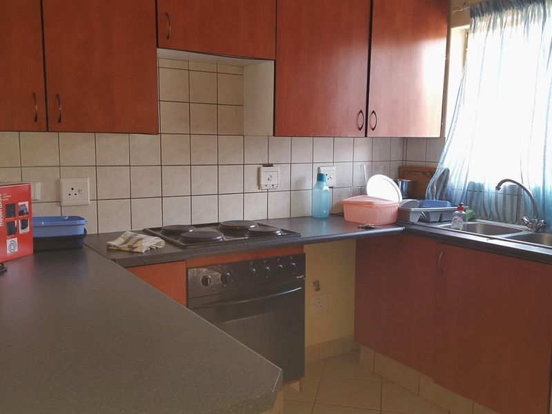 Functional kitchen featuring laminate cabinetry, electric hob, built-in oven, and a double bowl stainless steel sink with tiled splashbacks.