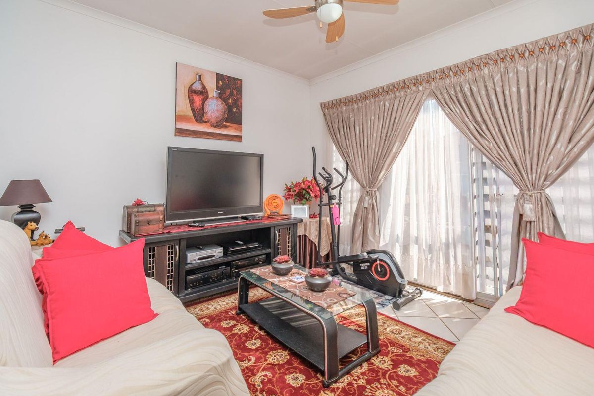 A living room featuring tiled flooring, a ceiling fan, and a sliding glass door providing access to the exterior.
