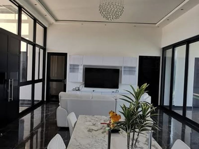 Modern open-plan living and dining area featuring high-end marble finishes, sleek black aluminium frames, and elegant recessed lighting.