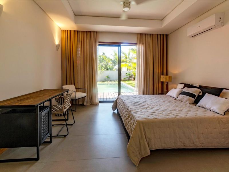 Spacious bedroom featuring large sliding glass doors that open directly onto a private pool deck, complemented by modern recessed ceiling lighting and air conditioning.