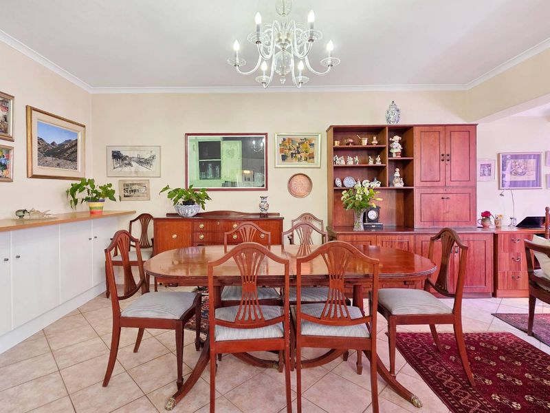 A well-maintained dining room featuring tiled flooring, built-in wooden cabinetry, and a classic chandelier, offering a warm and functional space for meals.
