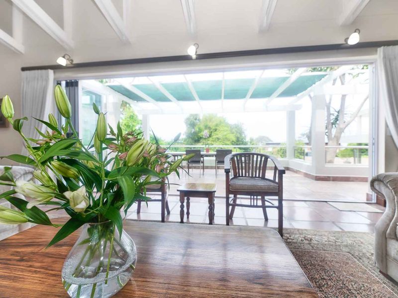 Spacious living room featuring exposed beam ceilings and large sliding glass doors that open onto a covered patio area.