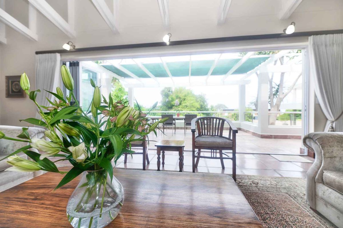 Spacious living room featuring exposed beam ceilings and large sliding glass doors that open onto a covered patio area.
