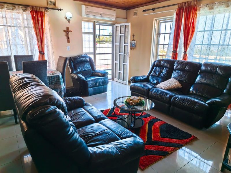 A living room featuring tiled flooring, a timber ceiling, and a split-system air conditioner, with direct access to an outdoor area via a security gate.
