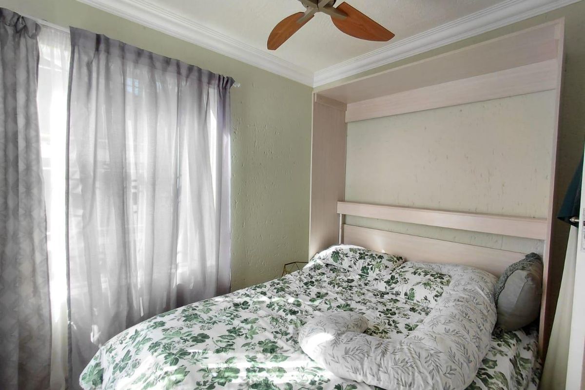A bedroom featuring a built-in headboard unit, crown molding, and a ceiling fan, providing a functional and comfortable sleeping space.