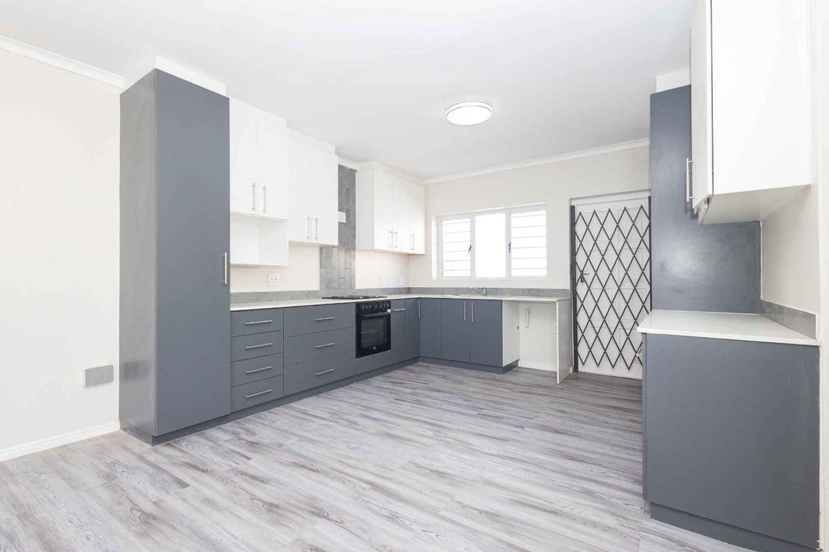 Modern kitchen featuring two-tone cabinetry, built-in oven and hob, laminate countertops, and durable wood-look flooring in a clean, open layout.
