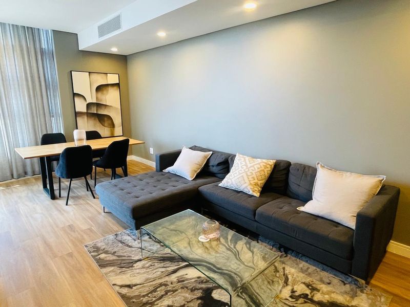 A modern open-plan living and dining area featuring laminate flooring, recessed downlighting, and integrated ducted air conditioning.