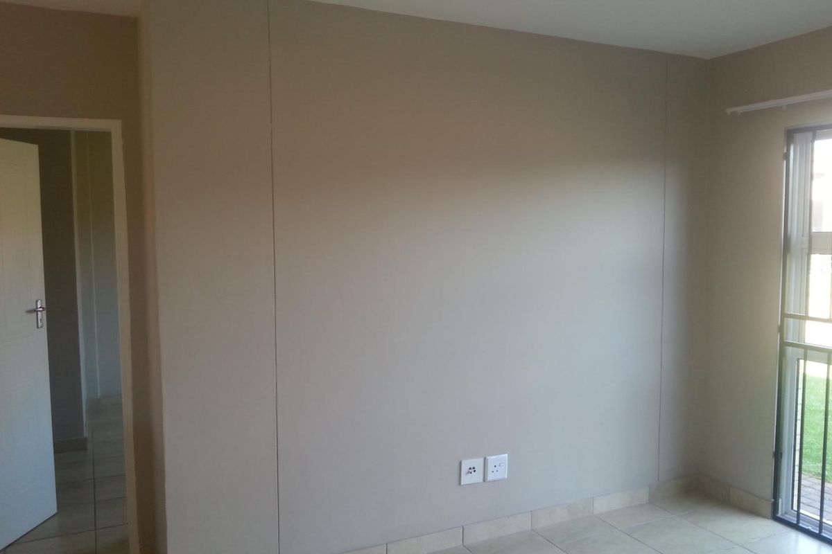 A neutral-toned bedroom featuring tiled flooring, a sliding door leading to an outdoor area, and integrated electrical outlets.