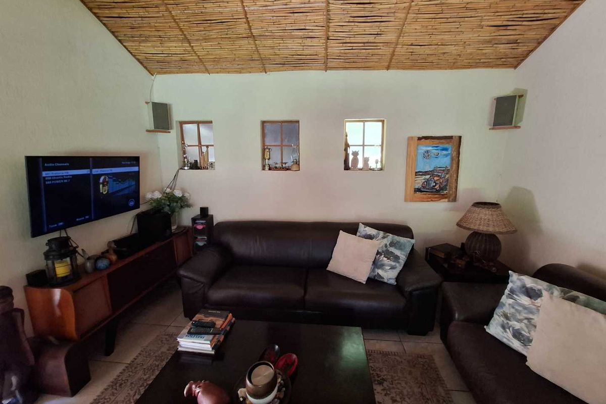 A cozy living room featuring a unique thatched ceiling, tiled flooring, and small inset windows, creating a rustic and inviting atmosphere.
