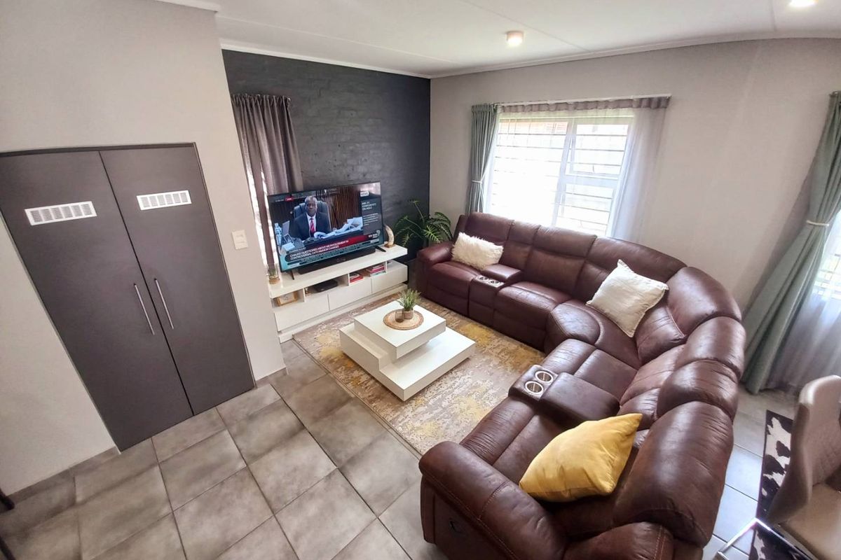 A comfortable living room featuring tiled flooring, a dark brick feature wall, and built-in storage cabinetry.