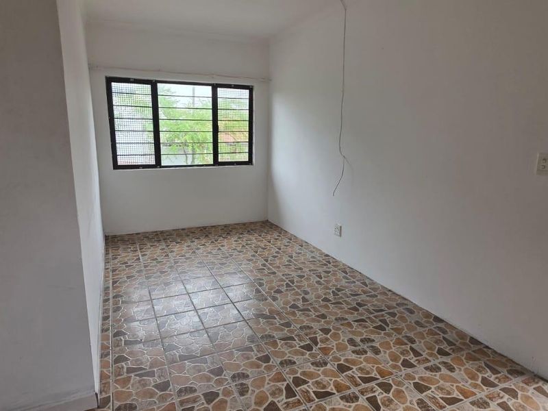 An empty bedroom featuring tiled flooring and windows with security bars. The space requires minor electrical repairs and cosmetic updates.