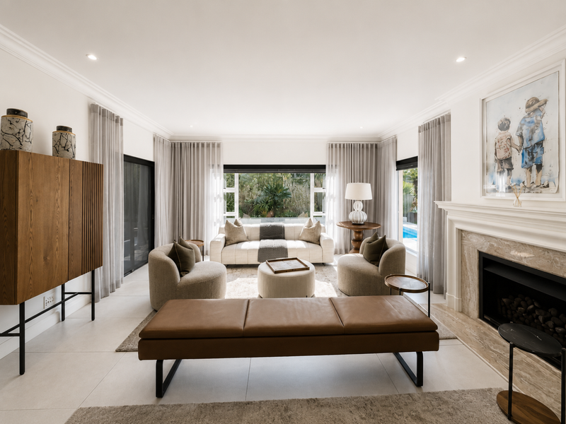 Elegant living room featuring a marble fireplace, large sliding glass doors leading to the pool area, and modern tiled flooring with recessed lighting.