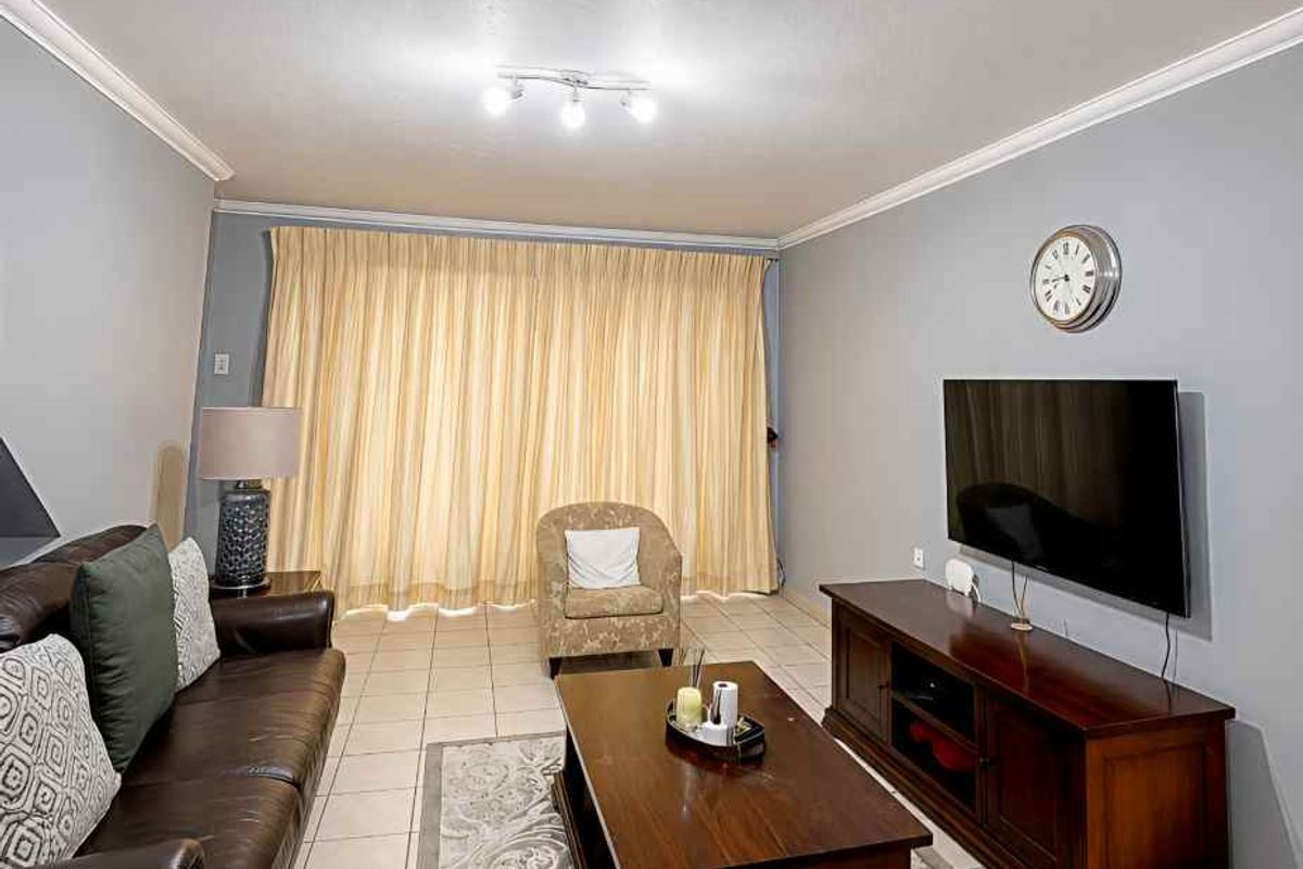 A comfortable living room featuring tiled flooring, ceiling coving, and track lighting, providing a functional space for relaxation.