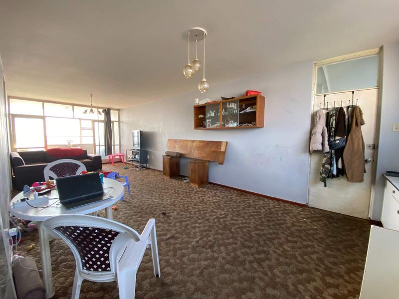 Spacious living area featuring carpeted flooring, built-in wall cabinetry, and large windows providing natural light.
