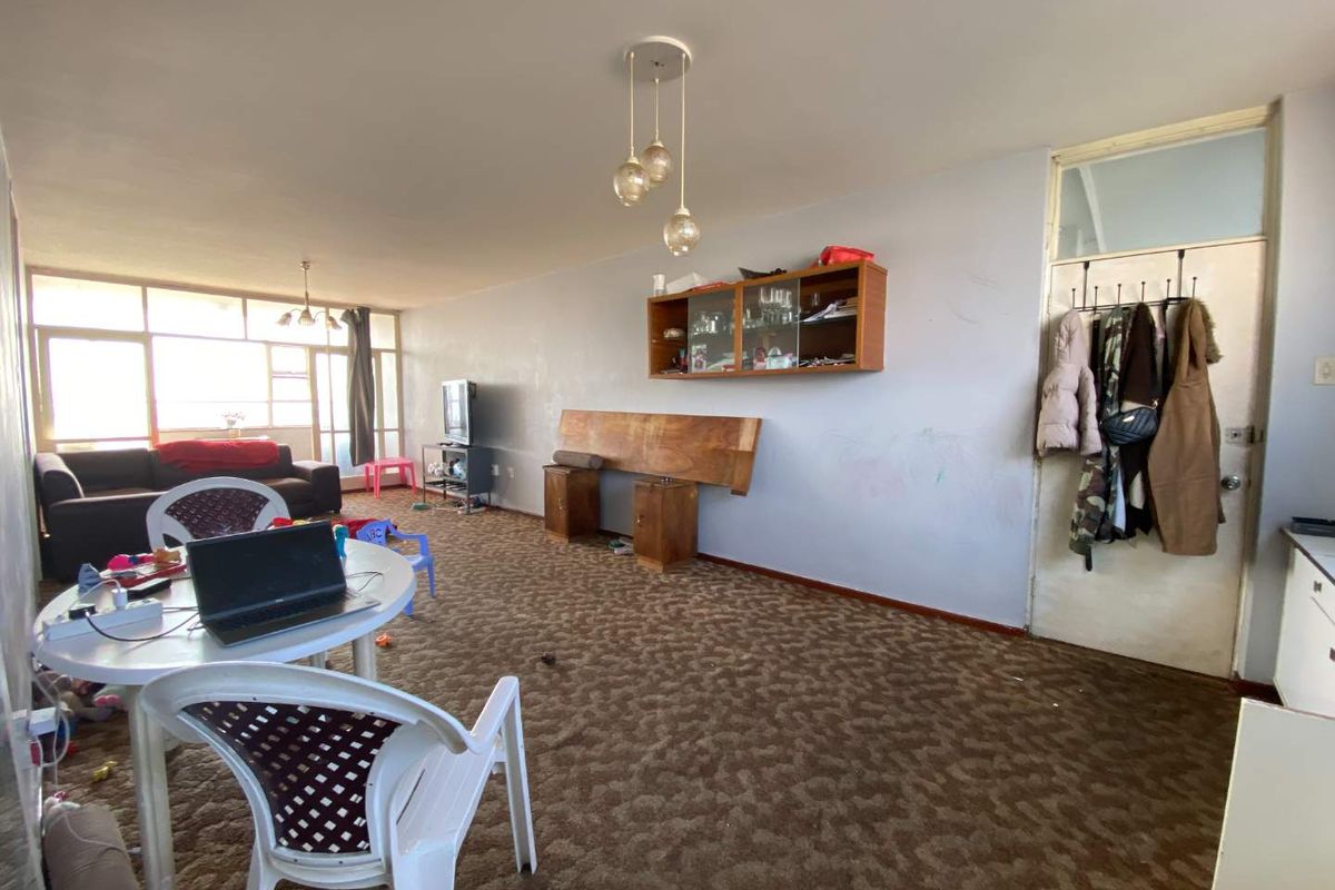 Spacious living area featuring carpeted flooring, built-in wall cabinetry, and large windows providing natural light.