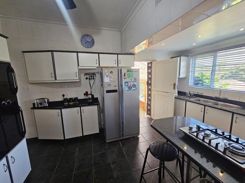 Functional kitchen featuring dark granite countertops, white cabinetry, gas hob, and tiled flooring with direct access to an outdoor area via a dutch door.